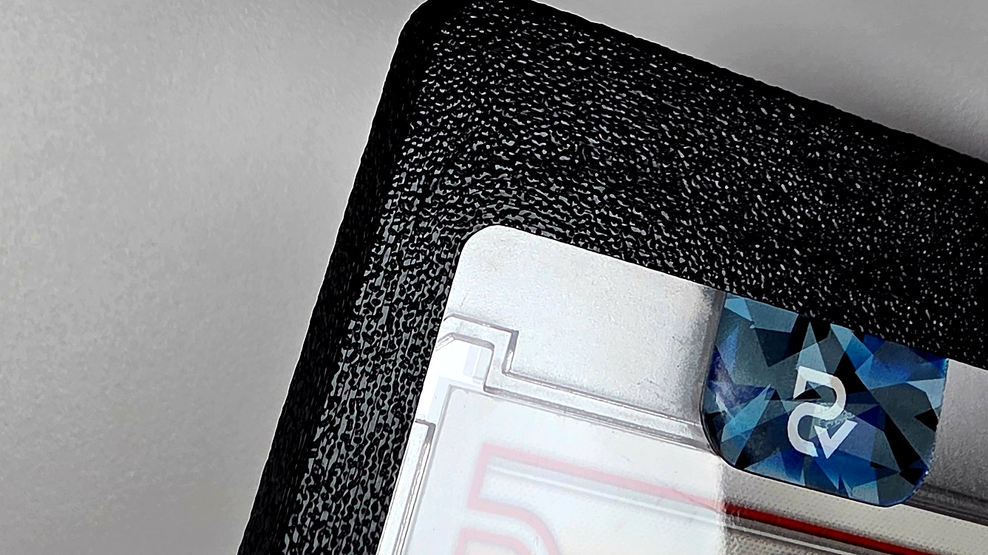 Corner of the black printed mag insert and bumper showing the pebbled, leather-like grain, with a magnetic card holder seated in the window