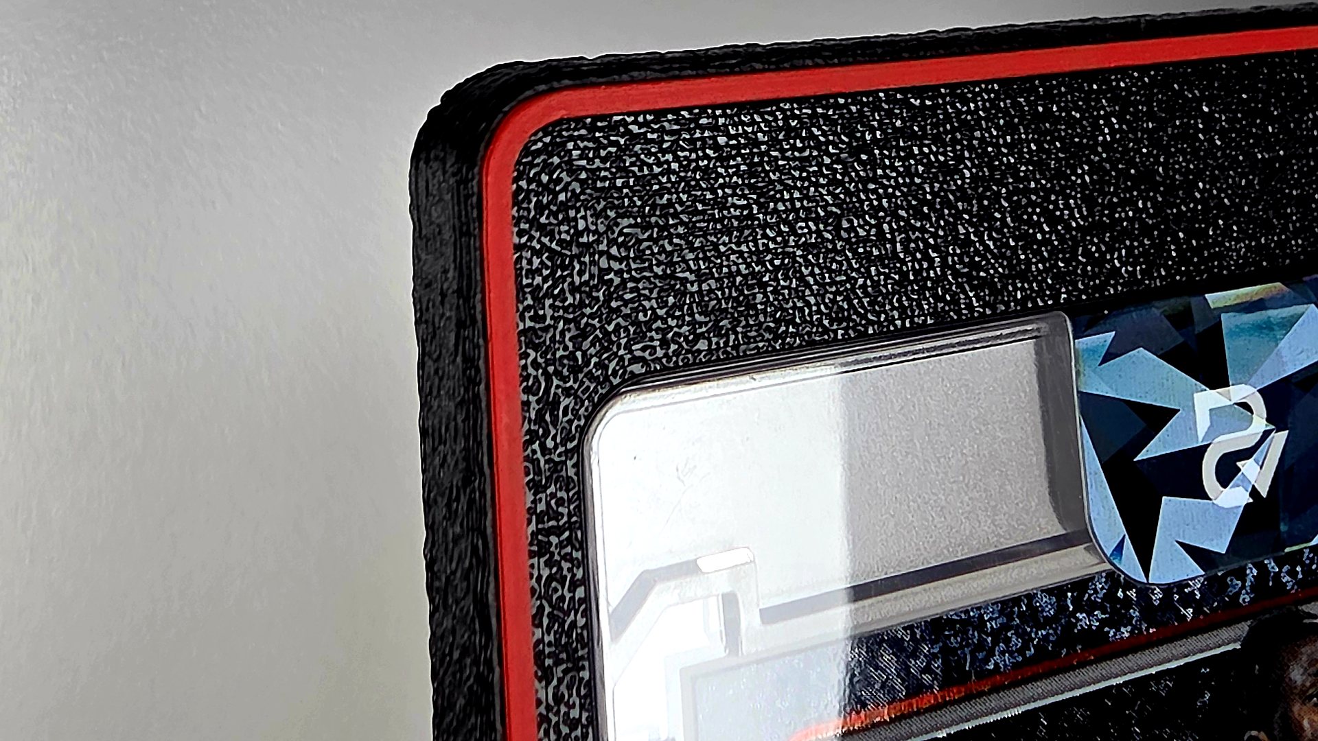 Corner of the black printed mag insert and bumper with a scarlet red ring line traced around the face, a magnetic holder seated inside